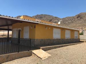 a yellow building with white doors and a fence at Casa Rural Aguilas (Murcia), Venta San Felipe in Águilas