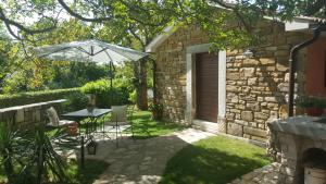 a patio with a table and an umbrella at Studio apartment Cami - Cottage with a soul in Gračišće