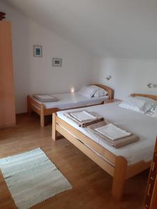 two beds in a room with wooden floors at Apartmani Stipanic Tivat in Tivat