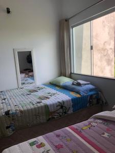 2 camas en una habitación con espejo y ventana en Casa no Atalaia en Salinópolis