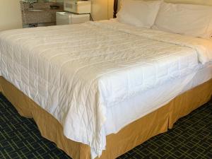 a large bed with a white blanket on it at Red Carpet Inn - Gettysburg in Gettysburg