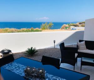 un patio con mesa, sillas y el océano en Il Tramonto Luxury House en Valledoria
