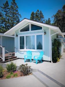 a tiny house with two blue chairs on a patio at Seafoam Lodge in Little River