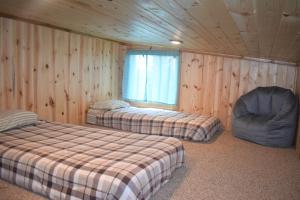 2 camas y una silla en una habitación con paredes de madera. en Drift Lodge en Island Park
