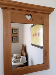 a mirror with a wooden frame in a bedroom at Fogadó a Suttogóhoz in Nagykörů