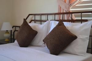 - un lit avec des oreillers blancs et une tête de lit en bois dans l'établissement 13 Sandy Beach Mackenzie, à Larnaka