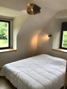 a bedroom with a white bed and two windows at Les gîtes du Plec - Piscine in Locoal-Mendon