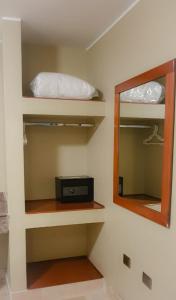 Habitación con estanterías con espejo y radio en Hostal Lince, en Lima