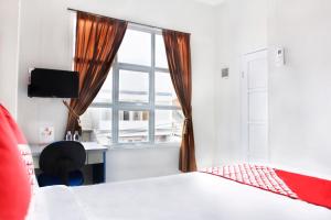 1 dormitorio con cama, escritorio y ventana en OYO 120 GP Residence, en Kampung Sawah
