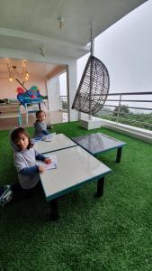 two children sitting at tables in a room with green carpet at The NEST, Tagaytay in Tagaytay
