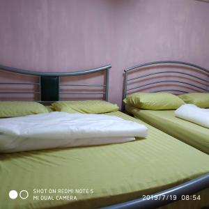 two beds sitting next to each other in a bedroom at Nora Damin Homestay Kampong Jalan Kebun in Kampong Lombong