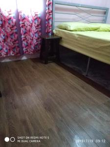 um quarto com 2 camas e piso em madeira em Nora Damin Homestay Kampong Jalan Kebun em Kampong Lombong