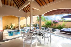 a dining room with a table and chairs and a pool at The Beverly Hills Bali Villas Resort in Jimbaran +72 photos