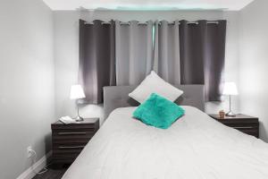 a bedroom with a white bed with a green pillow on it at ENTIRE 2 BEDROOM APARTMENT UPTOWN WATERLOO - e2 in Waterloo