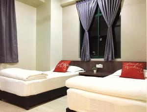 2 bedden met rode kussens in een kamer met een raam bij Amadel Residence 爱媄德民宿 1314 in Melaka