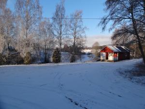 a snow covered road with a small red barn at Störsby Bed & Breakfast in Lappers