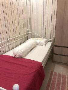 a bed with white pillows and a red blanket at Diantie's Room in Bogor