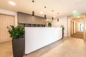 un hall de bureau avec un comptoir blanc et des plantes dans l'établissement Motel B, à Bocholt