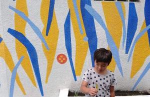 un joven parado frente a una pared en 青とサイダー, en Oshima