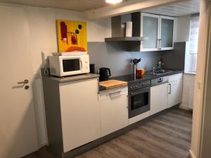 a kitchen with white cabinets and a microwave at Esprit-Apart-Hotel in Baden-Baden