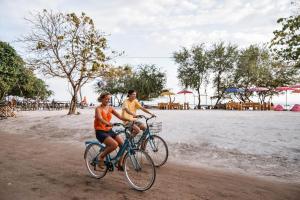 two people riding bikes on the beach at Bedolo Bungalows in Gili Air