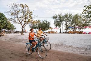 two people riding bikes on the beach at Bedolo Bungalows in Gili Islands