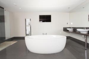 baño con bañera blanca grande y 2 lavabos en Sketchley Grange Hotel, en Hinckley