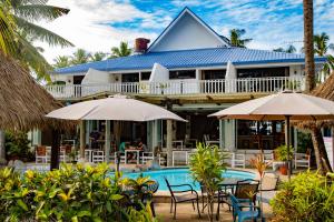 a house with a swimming pool and chairs and umbrellas at Aquarius On The Beach in Nadi