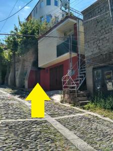 Ein gelber Pfeil, der auf ein Gebäude auf einer Straße zeigt. in der Unterkunft Dadu's Apartment in Tbilisi City