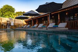 a swimming pool with lounge chairs and umbrellas at Royal Cottage Nusa Lembongan in Nusa Lembongan