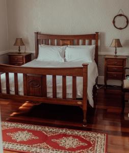 a bedroom with a wooden bed with white sheets and pillows at Railway Cottage in Bunbury