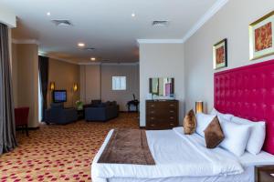 a hotel room with a large bed with a red headboard at Kingsgate Hotel Doha by Millennium Hotels in Doha