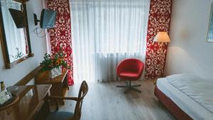 a bedroom with a red chair and a window at Hotel Büchner Garni in Bad König