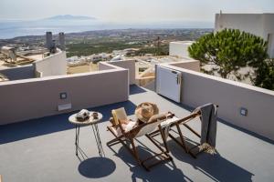 une personne assise dans une chaise sur un balcon dans l'établissement Echo Caves Suites, à Fira