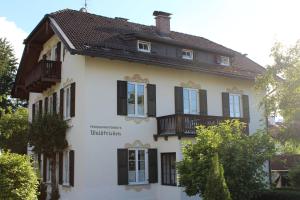 ein weißes Haus mit schwarzen Rollläden darauf in der Unterkunft Villa Waldfrieden - Ferienwohnungen und -Haus in Kochel