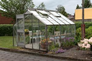 a greenhouse in a garden with chairs and flowers at Herligheden in Bjerringbro