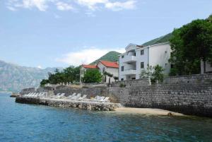 un groupe de chaises blanches sur un quai dans l'eau dans l'établissement Apartmani Račeta, à Kotor