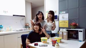 three girls sitting at a table in a kitchen at Coco Guest House in Incheon