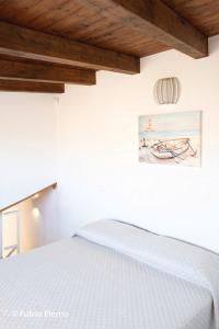 uma cama branca num quarto com tecto em madeira em Casa vacanza oscar em Castellammare del Golfo