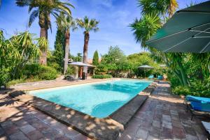 - une piscine avec des palmiers et un parasol bleu dans l'établissement Les Bastidieres - Cap Brun, à Toulon
