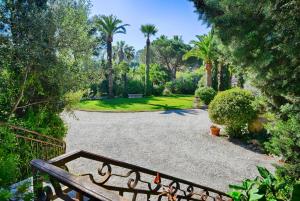 un jardin avec des palmiers et une allée dans l'établissement Les Bastidieres - Cap Brun, à Toulon