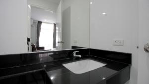 Baño en blanco y negro con lavabo y espejo en The Ocean Pearl en Pattaya South