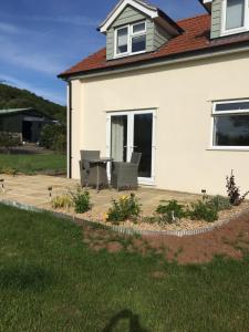 een patio met 2 stoelen en een tafel voor een huis bij The Annex, Fruit and Honey Farm in Bridgwater