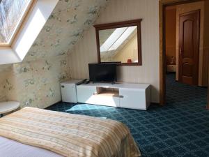 a bedroom with a bed and a tv and a mirror at Renesance Hotel in Zelenogradsk