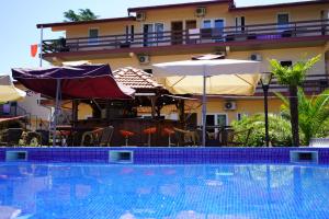 una piscina con ombrelloni e sedie accanto a un edificio di Ponto Hotel a Kobuleti