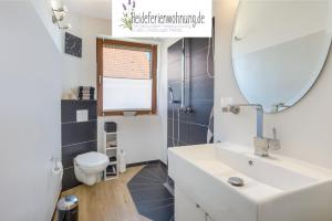 a bathroom with a sink and a mirror and a toilet at heideferienwohnung in Walsrode