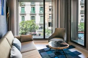 sala de estar con sofá, sillas y ventana grande en The Garden Suites, en Madrid