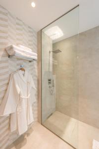 a bathroom with a shower and a white robe at The Garden Suites in Madrid
