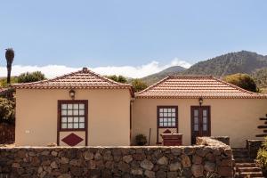 2 casas con una pared de piedra y montañas en el fondo en Los Hondos, en Garafía
