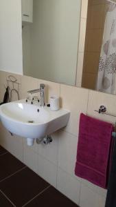 Brīvdienu māja INESE في بيرناتي: حمام مع حوض أبيض ومنشفة أرجوانية